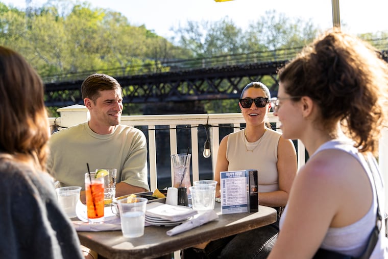 Luke Adams, 26, (left), and his wife Marina Adams, 27, (right), enjoy the evening with friends at the outdoor seating at the Manayunk Brewing Company in Philadelphia, Pa., on Thursday, April 20, 2023.