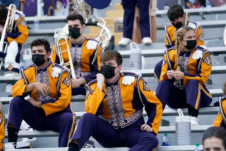 Masked members of the LSU marching band sit socially distanced from one another due to COVID-19 restrictions before a football game last year.