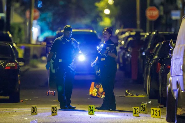 Philadelphia police Crime Scene Unit officers surrounded by multiple evidence markers along N. Alden Street above Girard Avenue after a multiple fatal shooting aearly Sunday morning July 21, 2024.