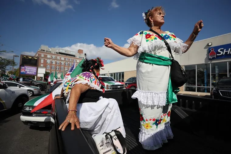 Maria Carmen Diaz (right) dance as Rosie Florencia (left) settles in the bed of a pick-up truck in the decorated car parade in Philadelphia, Sunday, Sept. 15, 2024. The event celebrates the 214th anniversary of Mexican independence.