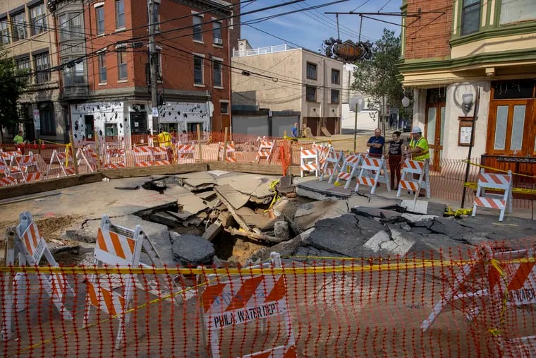 Philadelphia Water Department barricades surround the site of a water main break at the intersection of Bainbridge and South 6th Streets last month. Paying for such repairs has helped fuel rate increases.