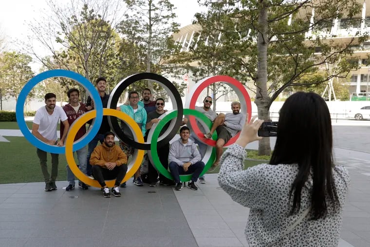 A group of students from Uruguay pose for a souvenir picture on the Olympic Rings set outside the Olympic Stadium in Tokyo on Saturday.