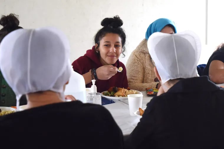 Syrian refugee Hevin Khilo (center) has a conversation and lunch with an Amish family on Saturday in Strasburg, Pa.