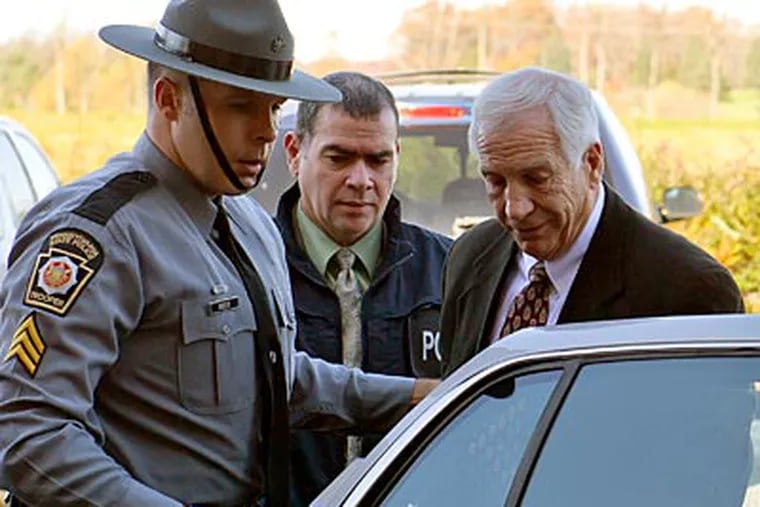 Former Penn State coach Jerry Sandusky is put in the back of a police car. (Andy Colwell/The Patriot-News/AP)