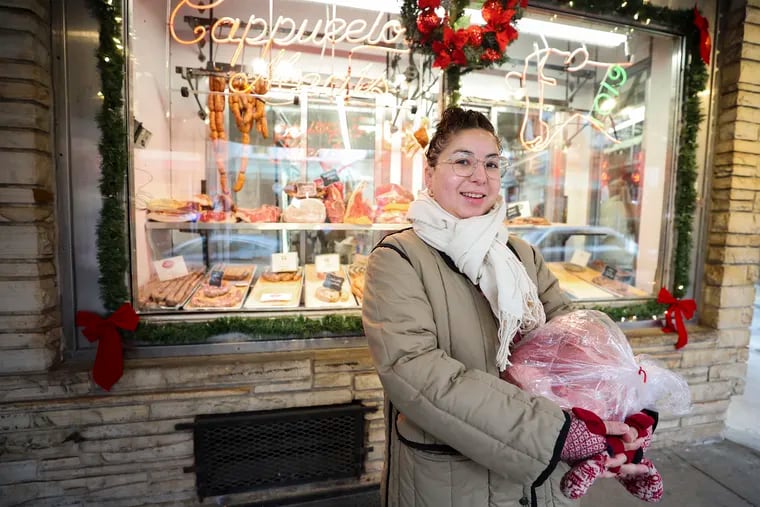 Alisha Miranda poses for a portrait with her recently purchased pork butt from Cappuccio's Meats for her annual Three Kings Day party, a Puerto Rican tradition, in South Philadelphia on Friday, Dec. 22, 2023.