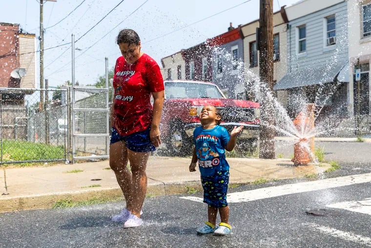 Alexandra Figueroa, 33, of Fairhill, cools off in the summer heat with her son Rubannyel Soto, 3, on Tuesday.