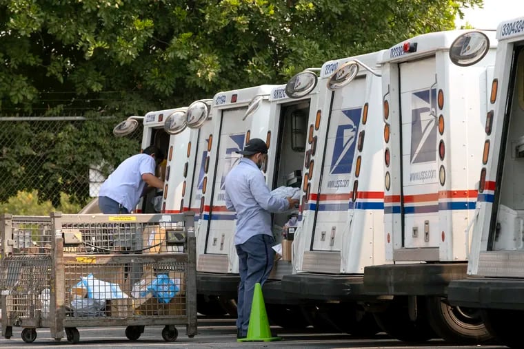 This Aug. 20 photo shows postal workers loading their mail delivery vehicles at the Panorama city post office in Los Angeles.