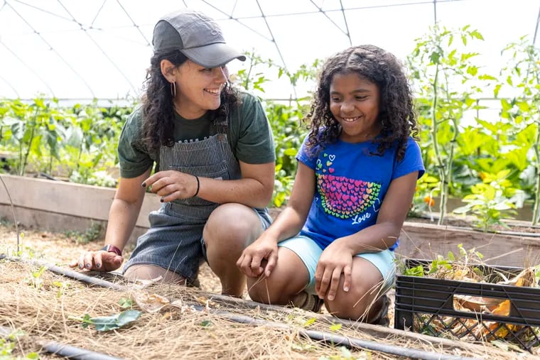 Ellie Kaplan, 29, of South Philadelphia, senior farm manager, is helping out Riam Harris, 9, who is with her mom, Tamyra Tutt, of Mount Airy, Pa., at the Nice Roots Farm in Philadelphia, Pa., on Saturday, June 15, 2024.