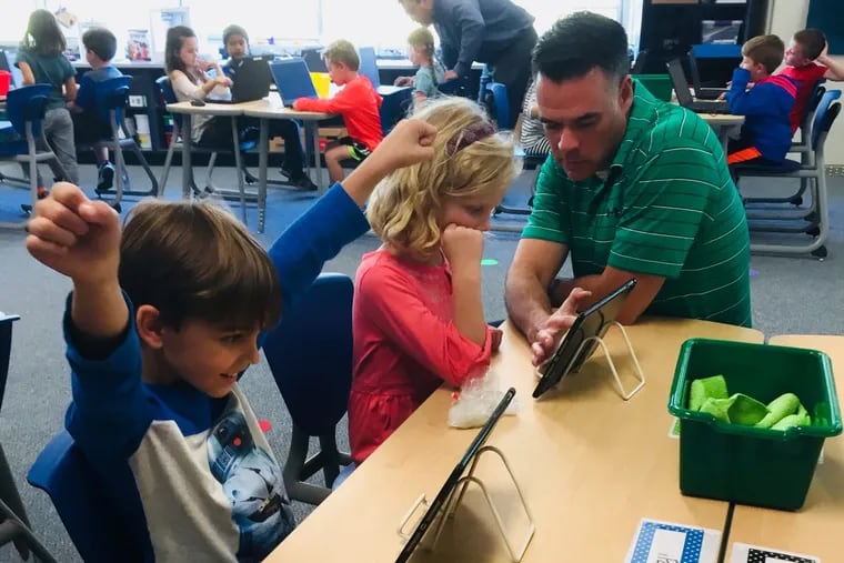 Joey Cervone and Hannah Dolan, first graders at Ridge Park Elementary School in Conshohocken, work with teacher Brian Adams on their first computer-coding lesson.