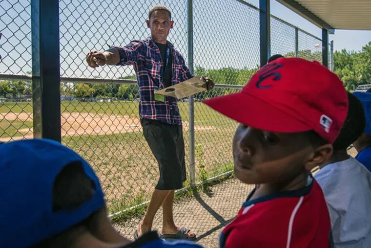 Bryan Morton, founder of North Camden Little League, assigns players positions before a game at Pyne Poynt Park in Camden (MICHAEL BUCHER/For The Inquirer)