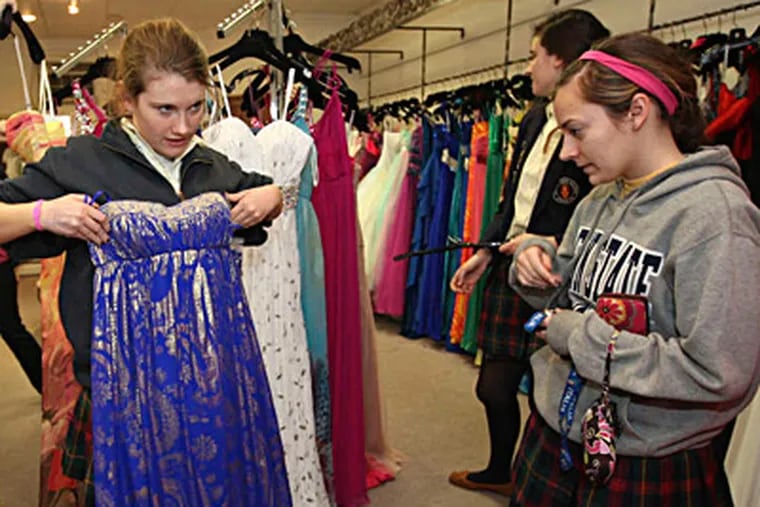 Kate Sullivan, 18, held up a gown last spring to see how it looked in the mirror as friend Lisa Bevilacqua, 18, watched. They both went to Merion Mercy Academy. MICHAEL BRYANT / Staff Photographer