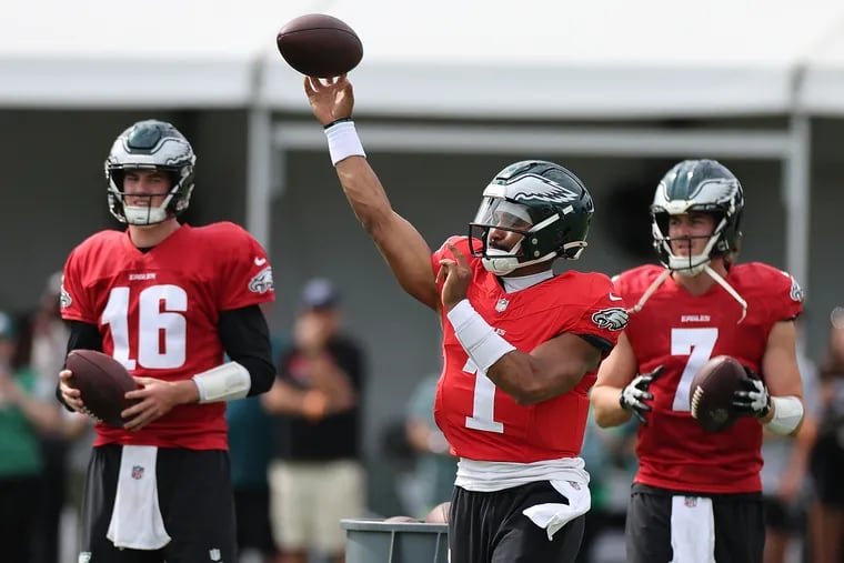 Eagles quarterback Jalen Hurts throws a pass as quarterback Tanner McKee (left) and quarterback Kenny Pickett (right) watch during a practice session at the NovaCare Complex on Sunday, Aug. 11, 2024.