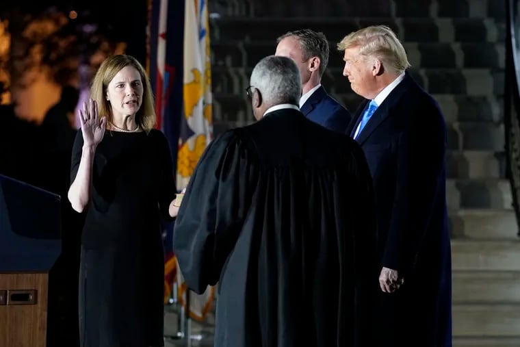 President Donald Trump watches as Supreme Court Justice Clarence Thomas administers the Constitutional Oath to Amy Coney Barrett on the South Lawn of the White House in Washington, Monday, Oct. 26, 2020, after Barrett was confirmed by the Senate earlier in the evening.