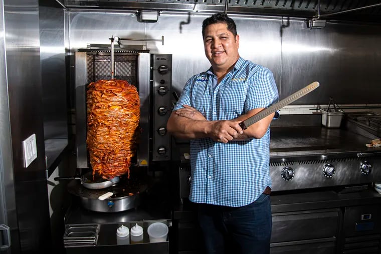 Chef, Carlos Aparicio, poses next to a meat trompo spit to prepare tacos al pastor on June 1, 2023 at El Chingon restaurant in Philadelphia, Pa.