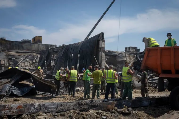 Workers clear debris at a shopping center damaged in a Russian rocket attack in Kremenchuk, Ukraine.